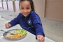 Aluna com alimentação escolar no prato